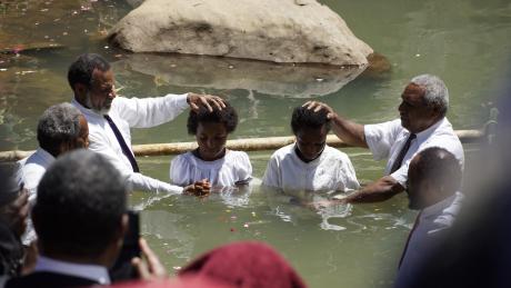 Two youths being baptised in Rum