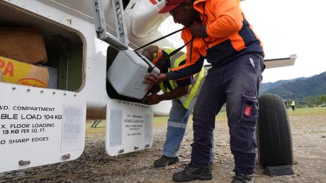 Telefomin traffic officer Ben Peter loading a vaccine eski into the aircraft