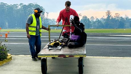 medevac patient and his dad getting moved into Hagen base on a trolley by traffic officer and Nathaniel