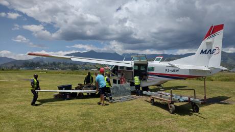 MAF plane on the ground in Goroka with playground materials loaded