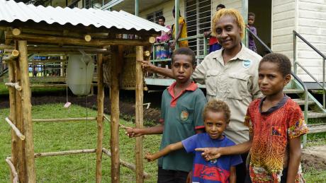 Yanu Kagayo standing with three local kids in front of the cleaning kit