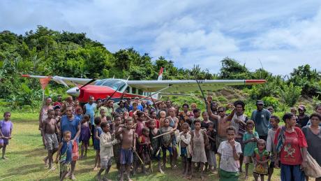 P2-AHP after its first landing at Moka airstrip with people joyfully gathered around the plane