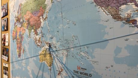 Large world map with strings and pins marking locations.