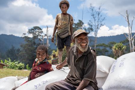 Dusin Villagers sit atop mounds of coffee waiting to be loaded on MAF plane.