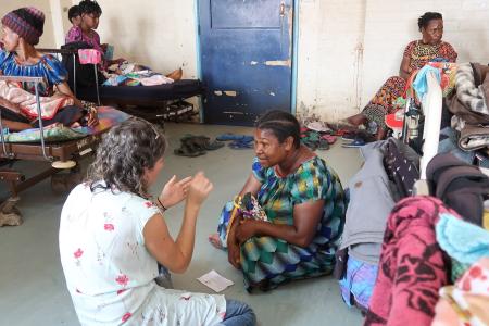 Michelle talking to a mother in hospital while others watch from their beds