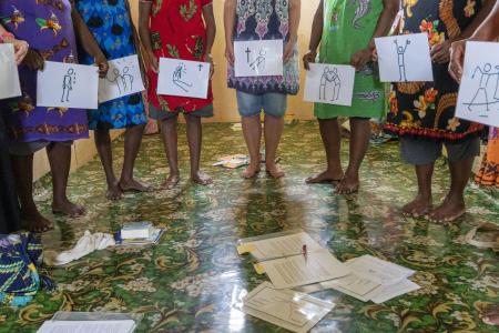 Inmates standing up with holding pictures of previous teaching