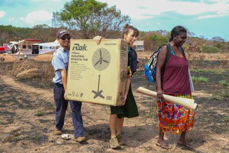 MAF pilot and teachers carry school equipment.