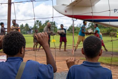Boys watch as a plane is unloaded at a remote airstrip