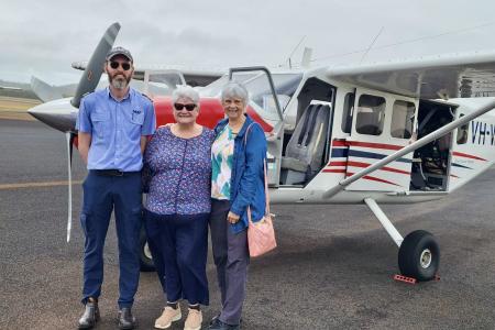 Pilot and passengers standing on tarmac in front of GA8 aircraft