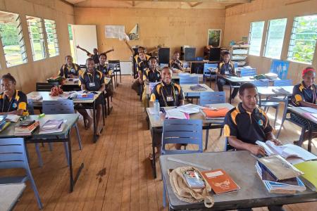 Happy students in classroom at Mougulu Secondary School with new chairs