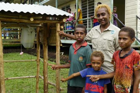 Yanu Kagayo standing with three local kids in front of the cleaning kit