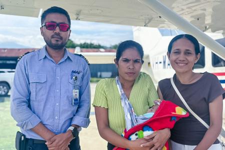 Three people and a baby post in front of a MAF plane.