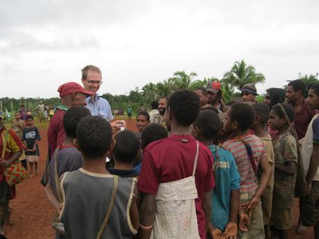 Papua New Guinean people surrounding piltio in marketplace