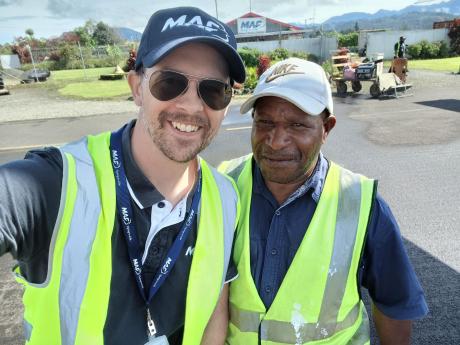 Two men in high-visibility vests standing on runway tarmac