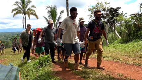 Titus Yabua and others carrying the patient on a stretcher to the aircraft