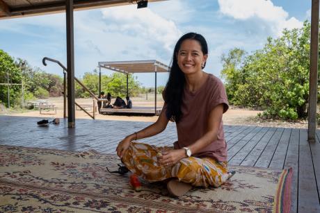 School principal sitting on mat on school verandah