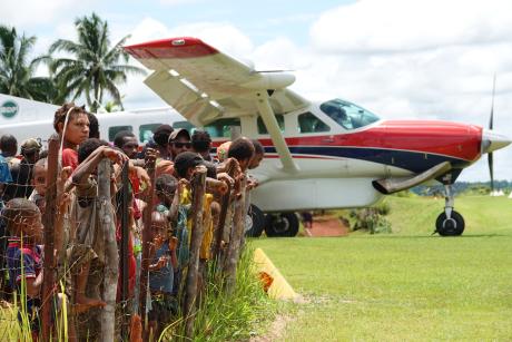 children and teenagers along the airstrip perimeter fence seeing the plane of with Babra's medevac