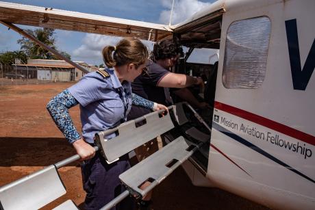 Pilot lifting scoop stretcher into aircraft
