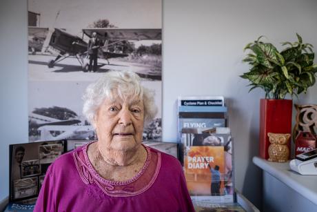 Elderly lady in office in front of photo of plane
