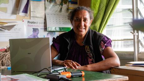 A woman sits at a desk and smiles