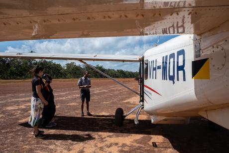 People preparing to board aircraft on dusty airstrip