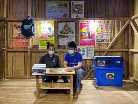 Two people sit at a table under electric light