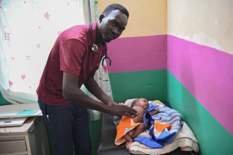 Dr Joseph Maker examines a baby with malaria