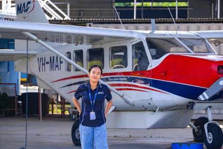 A woman stands in front of a small aeroplane