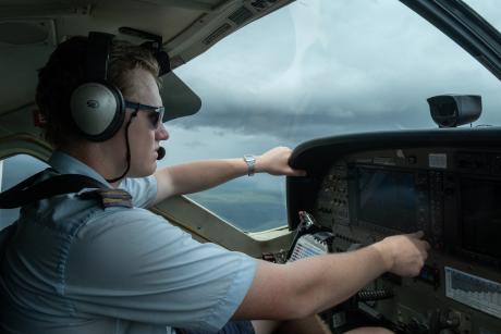 Inside cockpit pilot flying aircraft with rain clouds close by